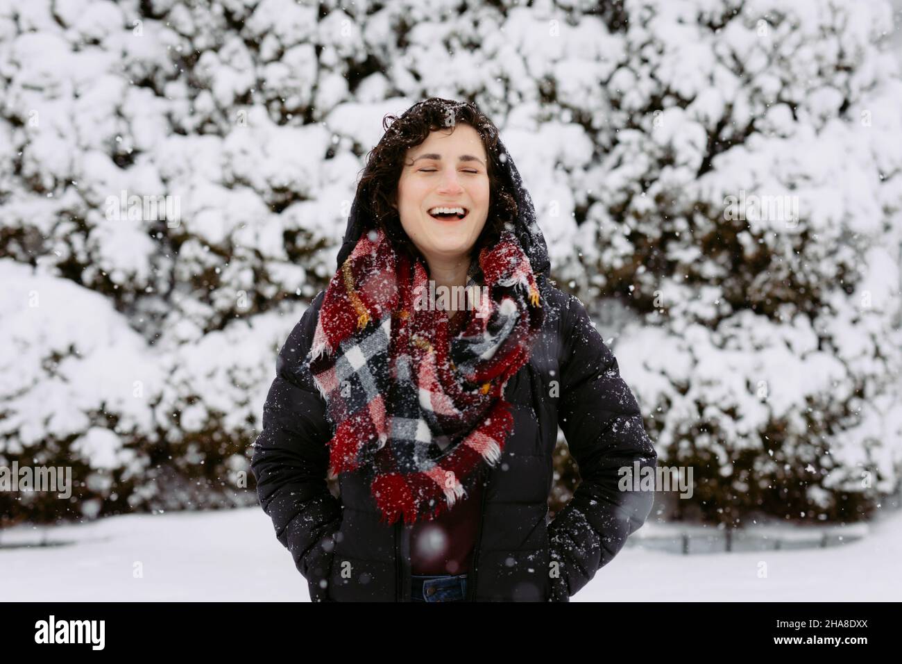 Donna in cappa e sciarpa rossa sorridendo e ridendo fuori sulla neve Foto Stock