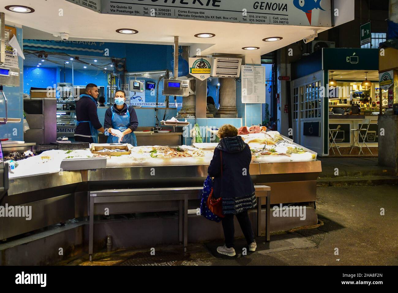 Una signora che acquista pesce fresco al banco del mercato Orientale coperto (MOG) nel centro di Genova, Liguria, Italia Foto Stock