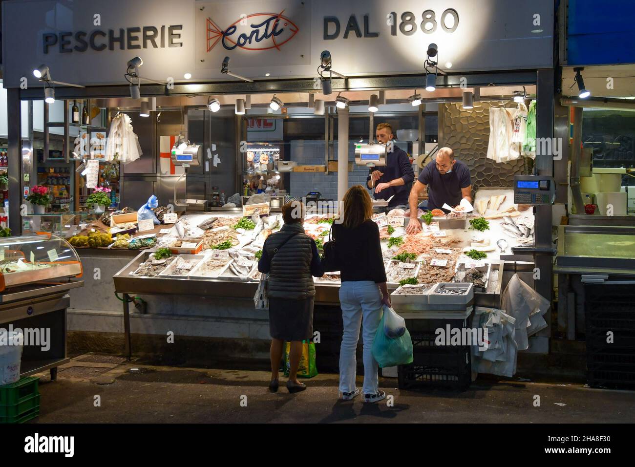 Donne che acquistano pesce fresco al banco del mercato Orientale coperto (MOG) nel centro di Genova, Liguria, Italia Foto Stock