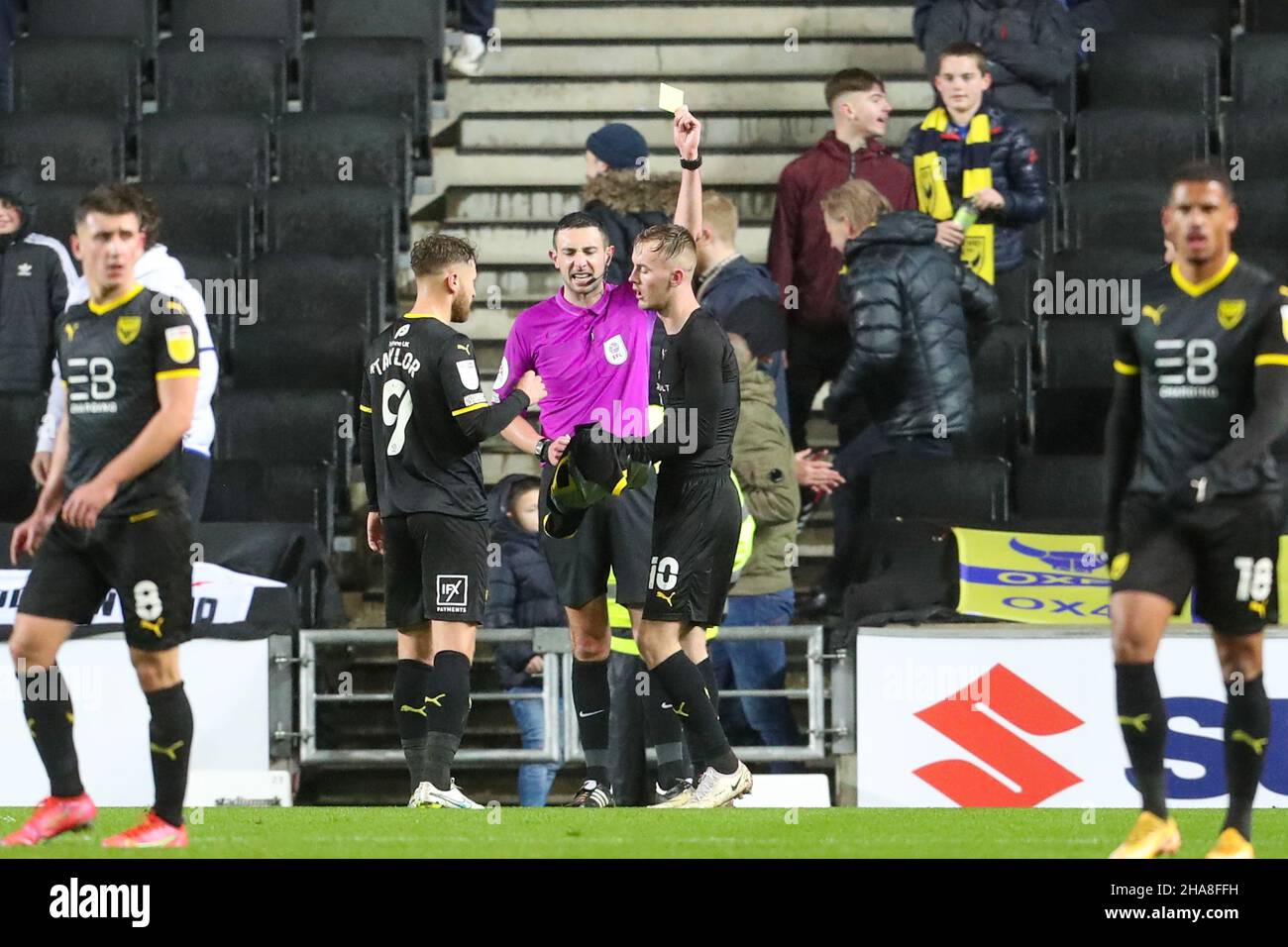MILTON KEYNES, GBR. DIC 11TH. L'arbitro Tom Reeves mostra una carta gialla a Mark Sykes di Oxford United dopo la celebrazione del suo gol durante la seconda metà della partita Sky Bet League 1 tra MK Dons e Oxford United allo Stadio MK, Milton Keynes sabato 11th dicembre 2021. (Credit: John Cripps | MI News) Credit: MI News & Sport /Alamy Live News Foto Stock