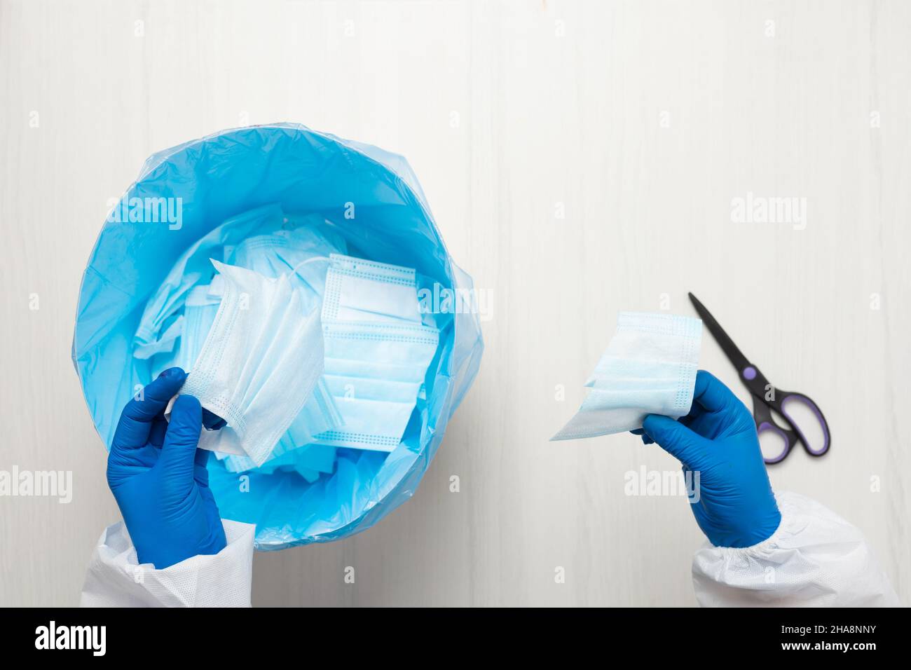 Le mani con le forbici tagliano attraverso la maschera medica. Foto Stock