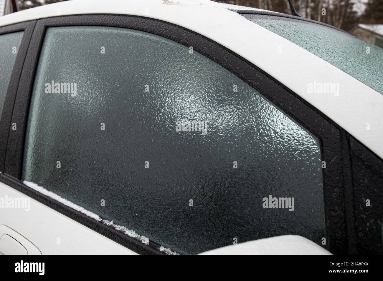 Strato di pioggia di ghiaccio che copre la finestra di vetro dell'automobile nella fredda giornata di inverno all'aperto. Concetto di condizioni meteorologiche estreme. Foto Stock