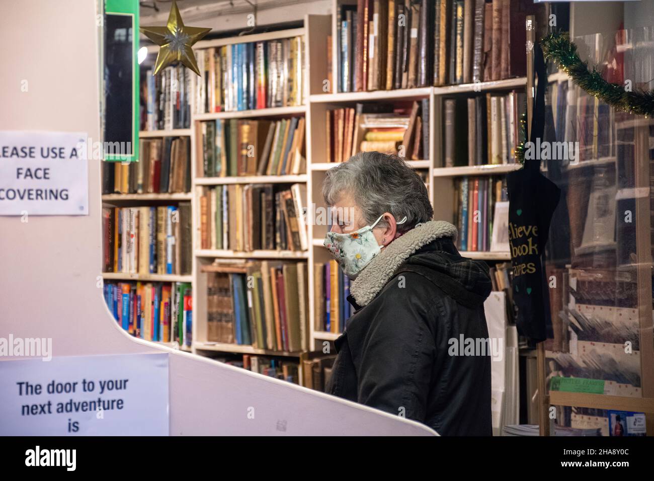 Donna che indossa una maschera di navigazione in un negozio di libri, dicembre 2021, durante la pandemia di covid-19, Regno Unito Foto Stock
