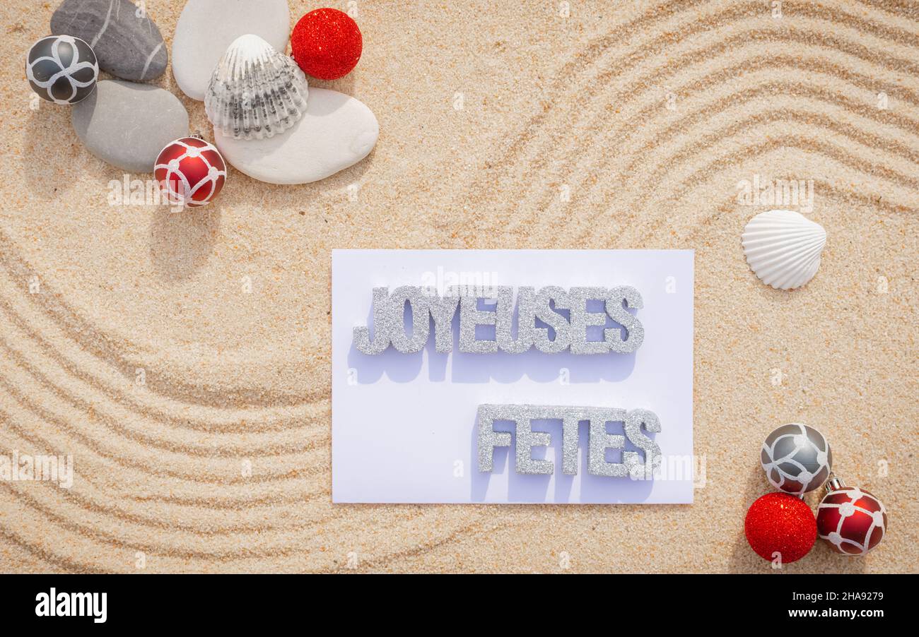 Sfondo sabbia di mare, sabbia fine spiaggia con ciottoli e baubles di Natale. Messaggio buone feste. Foto Stock