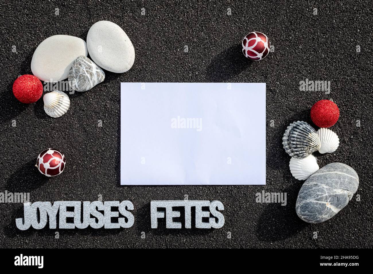 Sfondo sabbia di mare, sabbia fine spiaggia con ciottoli e baubles di Natale. Messaggio buone feste. Foto Stock