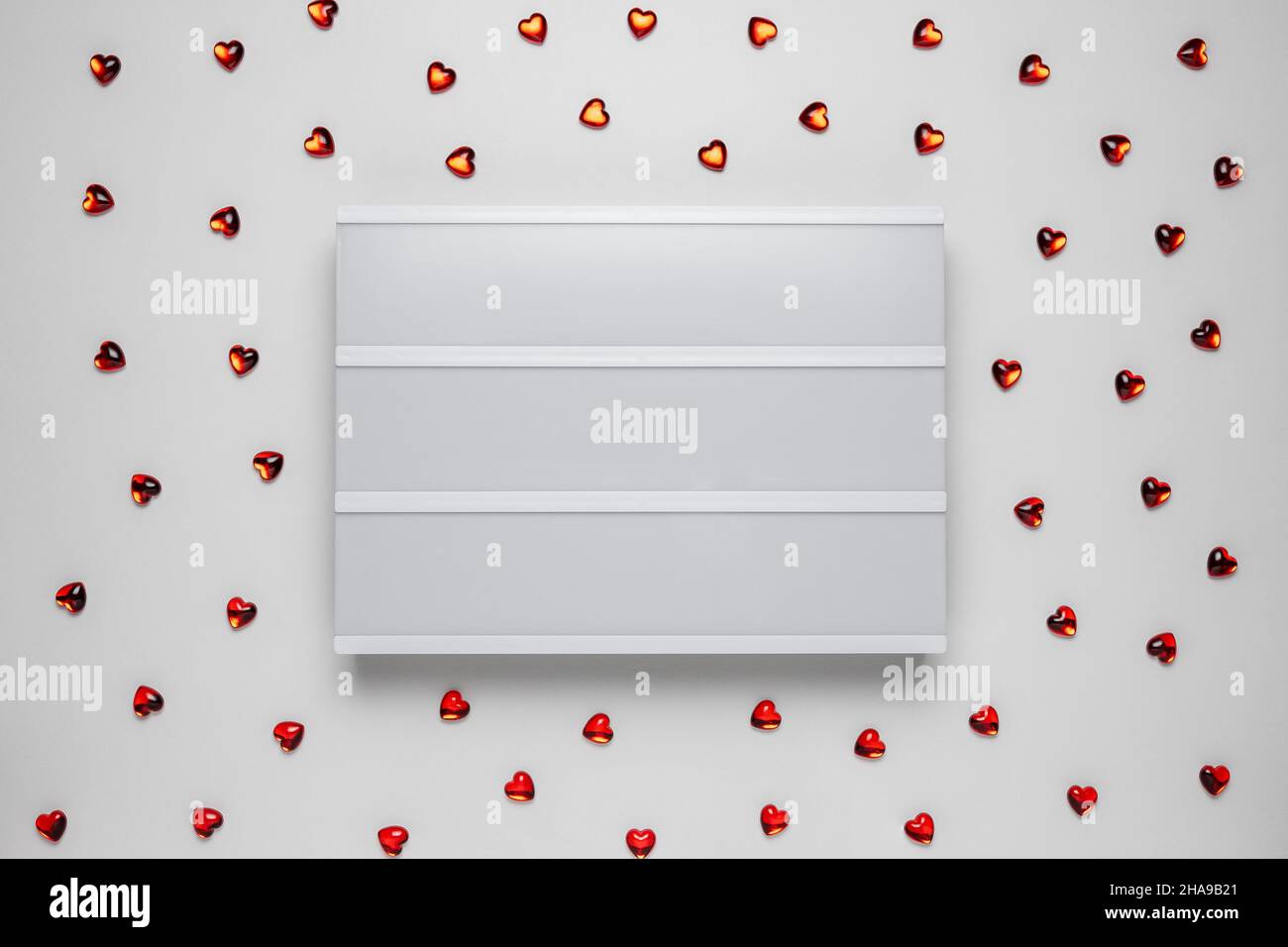 Scatola luminosa con cuori decorativi su sfondo bianco. Concetto di vacanza. Foto Stock
