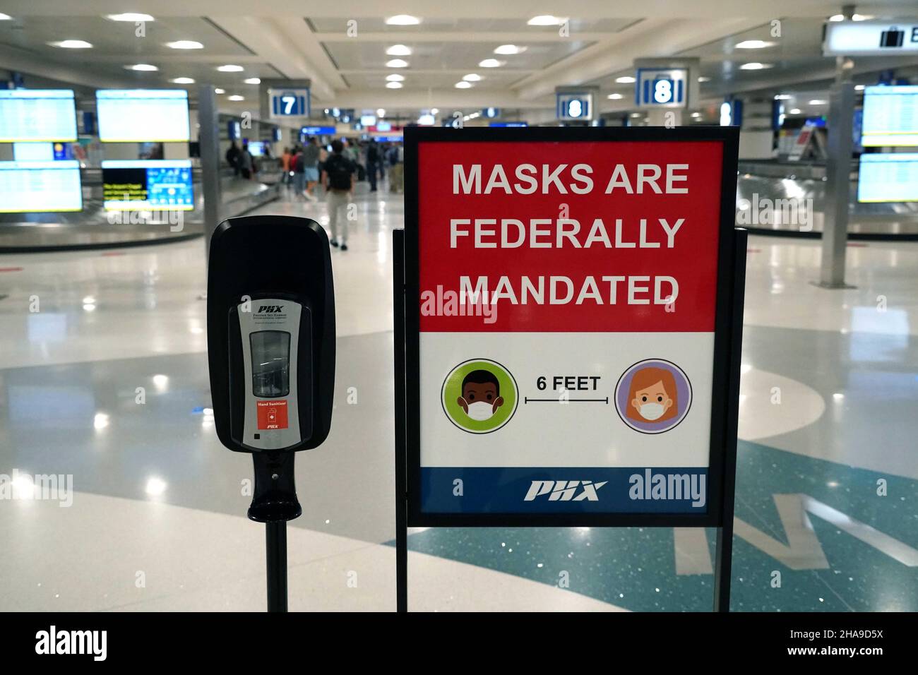 Un cartello con la maschera federale e un dispenser di disinfettante per le mani nell'area ritiro bagagli del terminal 4 dell'aeroporto internazionale Sky Harbor di Tuesda Foto Stock