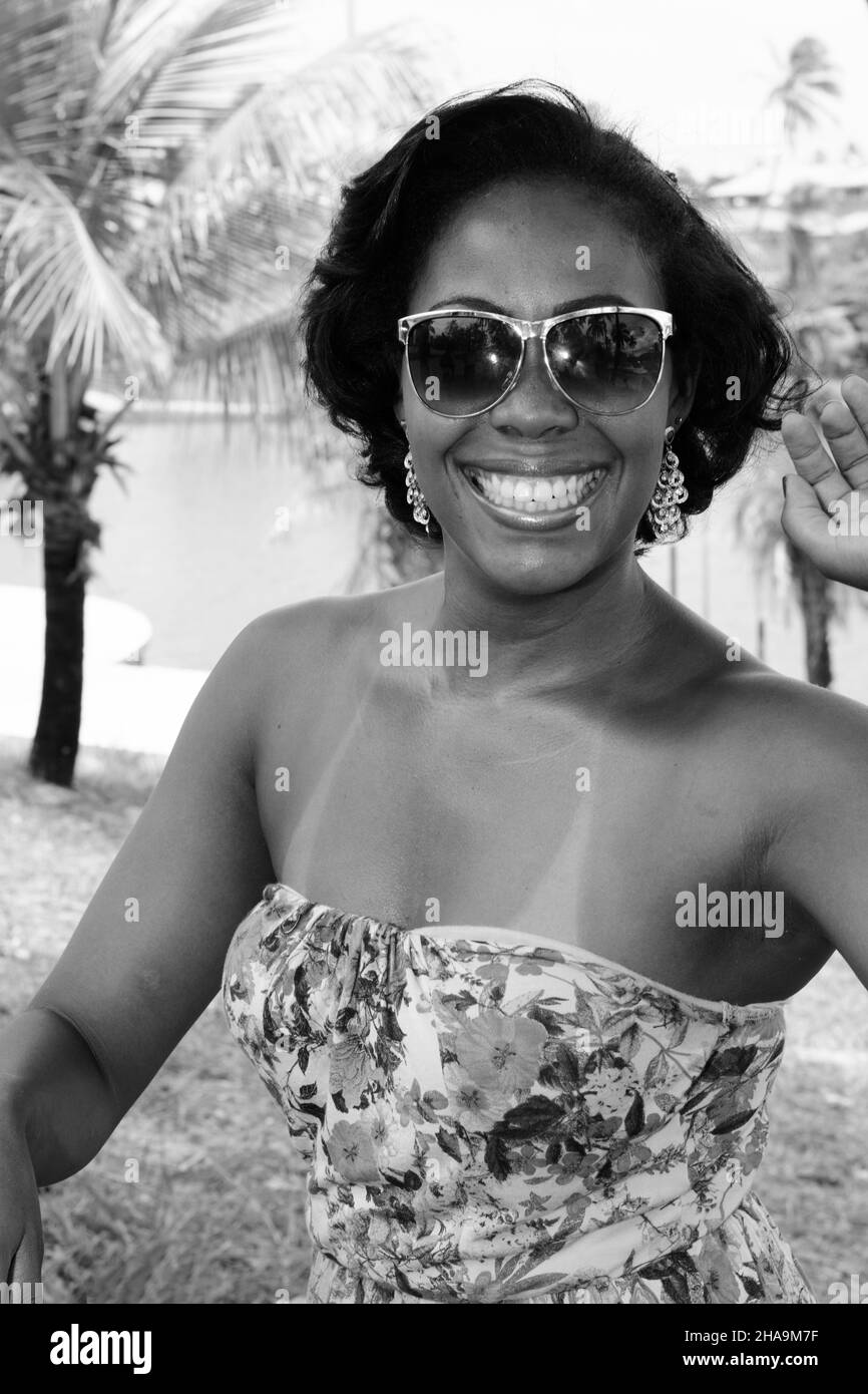 Donna nera in posa per la foto. Sorride e guarda la fotocamera. Sullo sfondo, la natura in alberi e piante. Salvador, Bahia, Brasile. Foto Stock