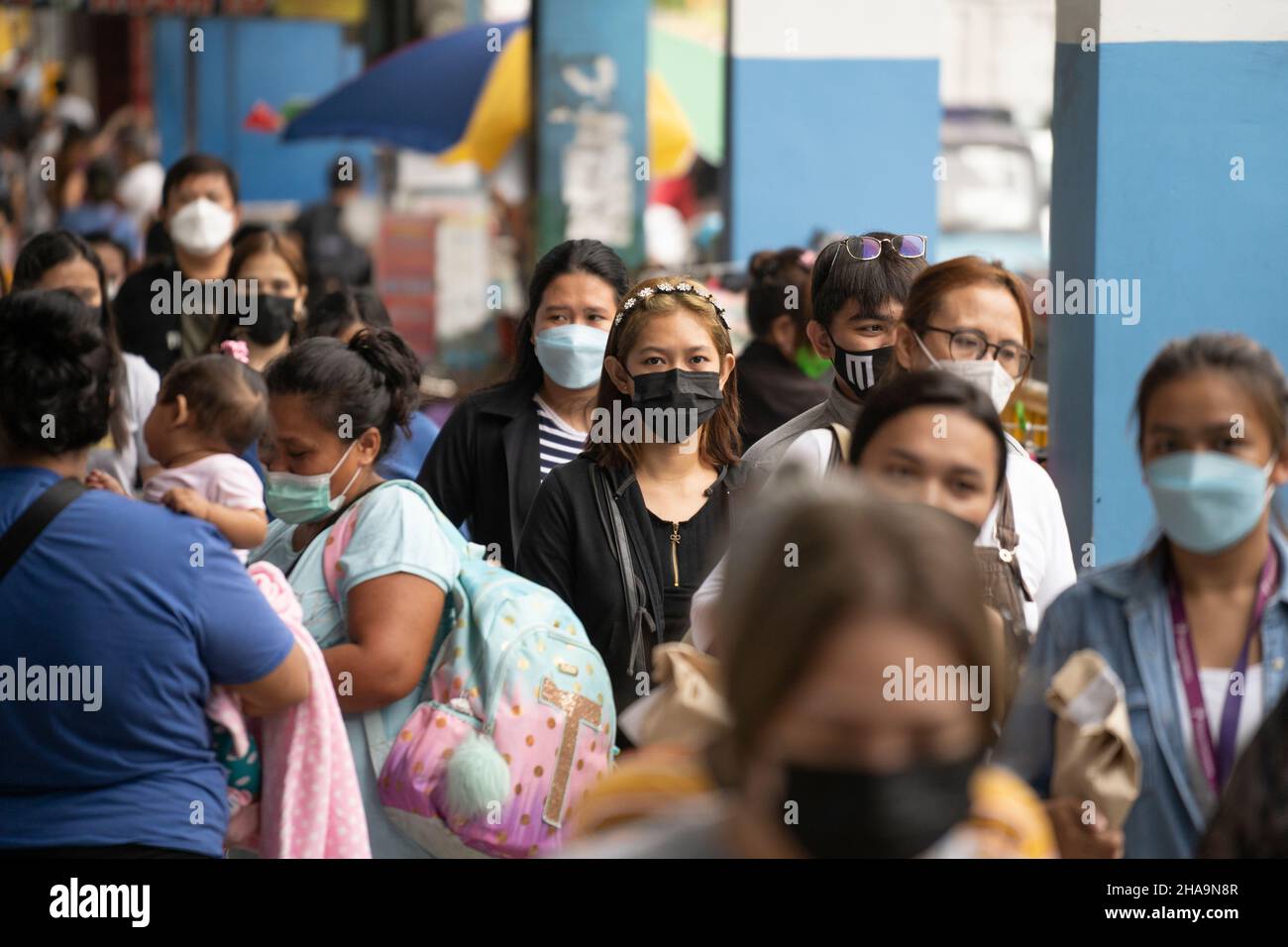 La gente nelle Filippine che cammina lungo una strada che indossa le maschere facciali, l'uso di maschere facciali nei luoghi pubblici e negli stabilimenti è obbligatorio. Foto Stock