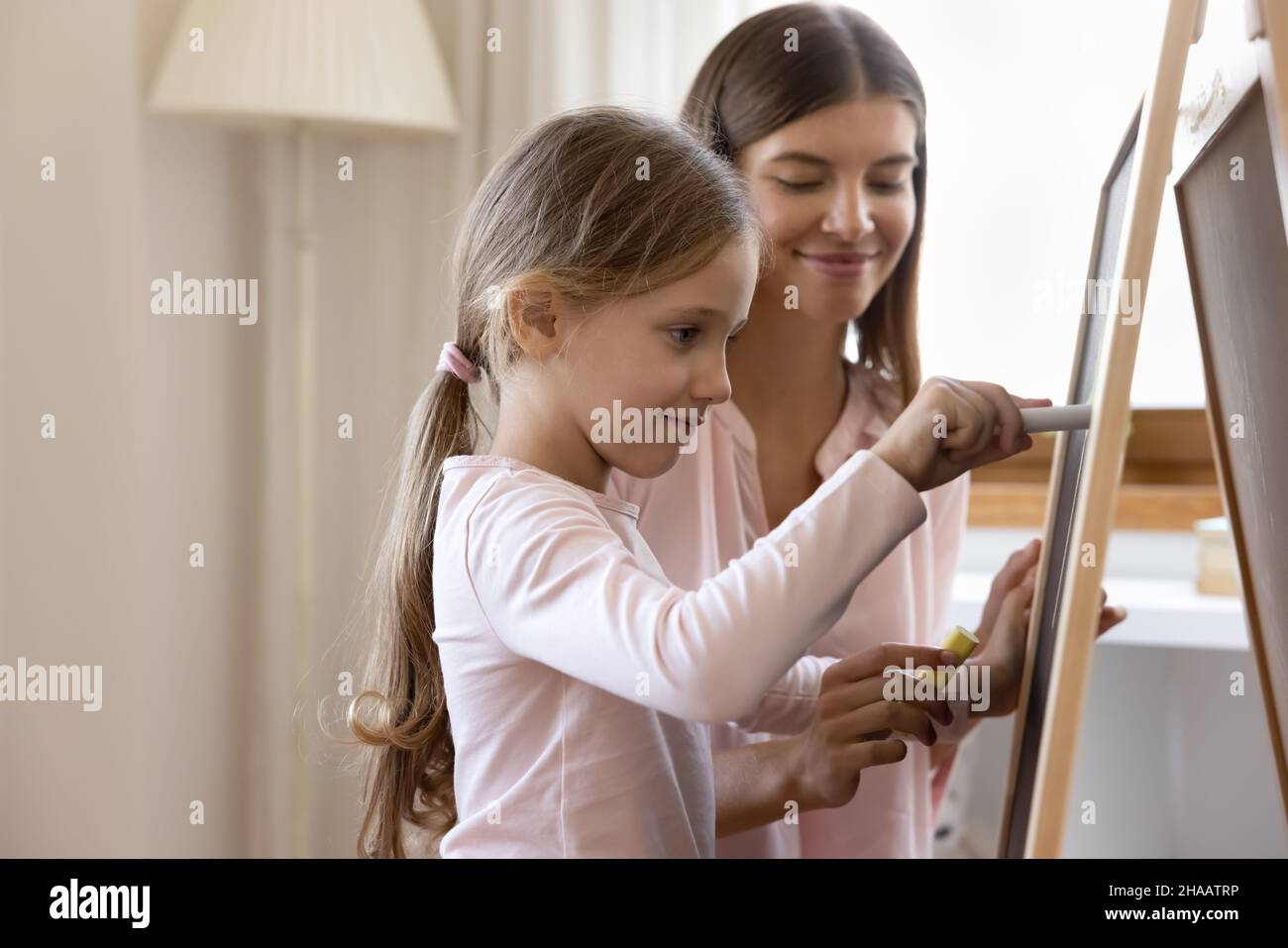 Ragazza carina messa a fuoco bambino imparando a scrivere, disegno con gesso Foto Stock