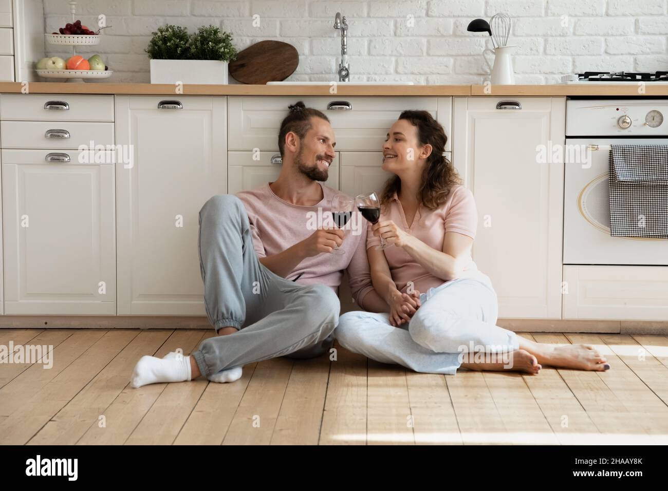Allegro dolce giovane coppia di canti seduta sul pavimento in cucina Foto Stock