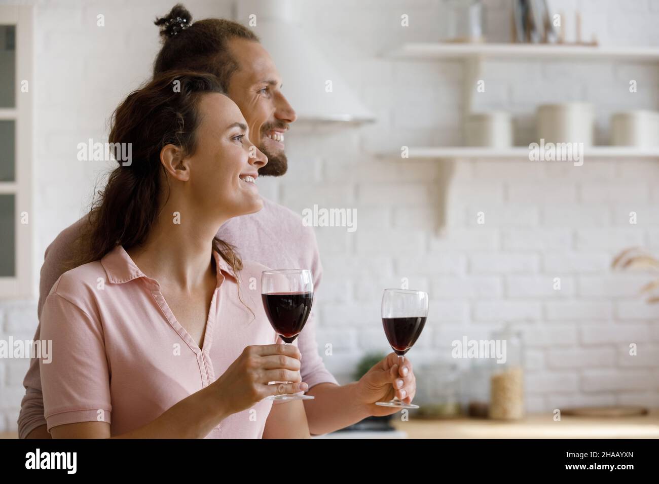 Felice coppia gioiosa che tiene i wineglasses, bevendo il vino rouge in cucina Foto Stock
