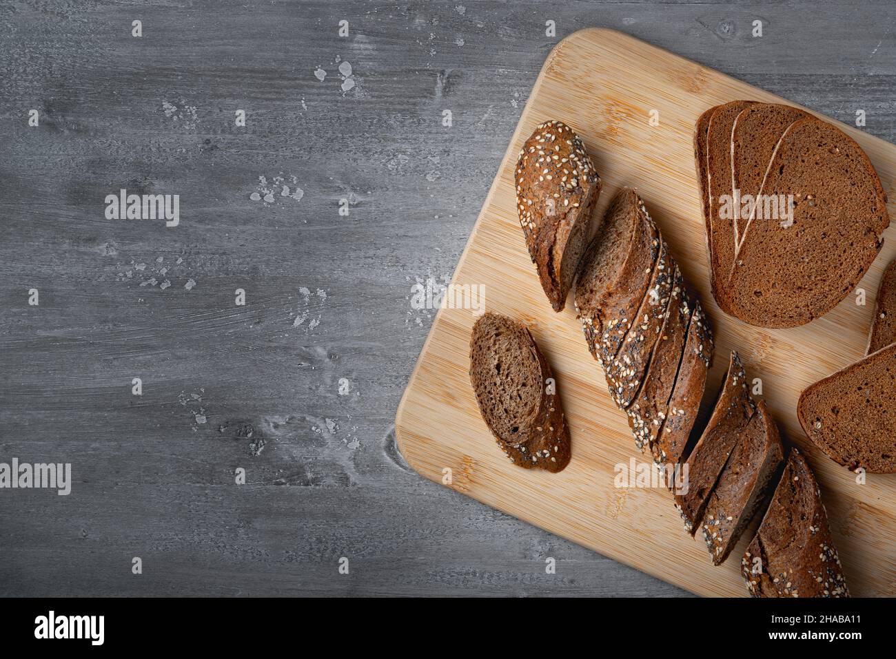 Pane di segale affettato su un tagliere di legno con grano Foto Stock