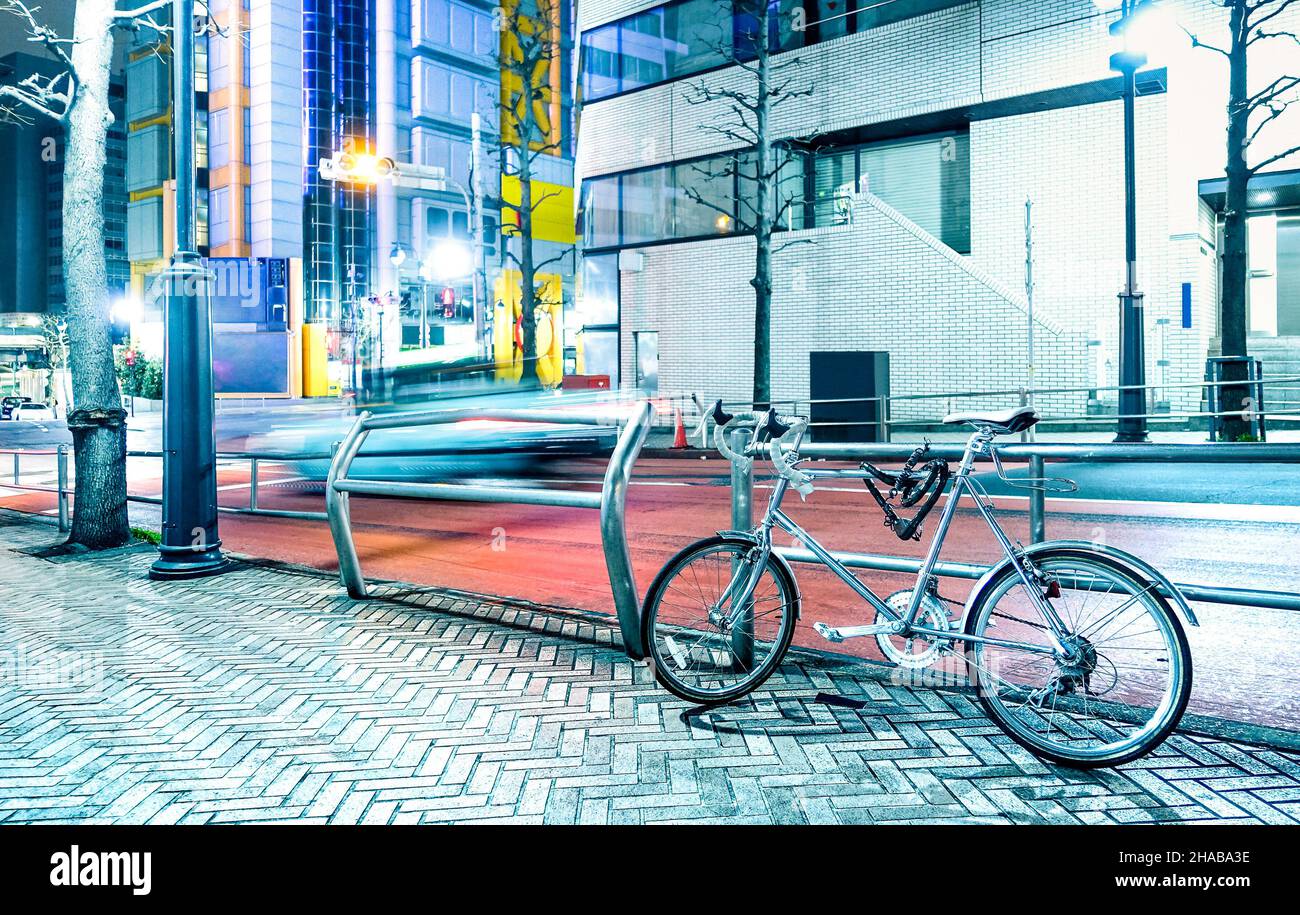 Scena notturna con bicicletta parcheggiata e auto a velocità sfocata nel centro della città di Tokyo capitale del Giappone - Urban Travel Concept Foto Stock