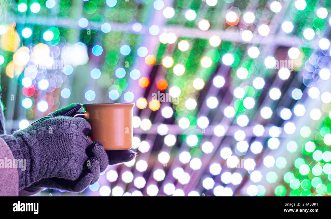 Donna che tiene la tazza con VIN brulé o cioccolata calda al mercatino di natale. Foto Stock