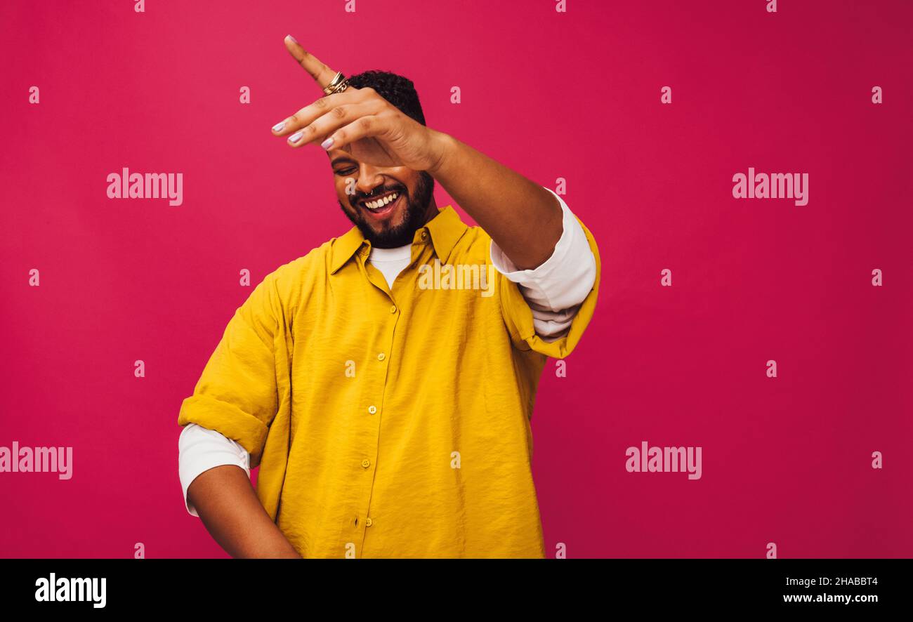 Giovane che balla alla musica in uno studio. Felice giovane uomo sorridendo allegro mentre ascoltava la sua musica preferita. Bel giovane uomo in piedi da solo a Foto Stock