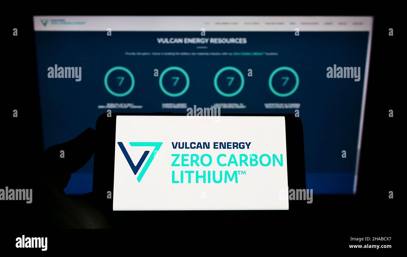 Persona che tiene il telefono cellulare con il logo della società australiana Vulcan Energy Resources Ltd sullo schermo di fronte alla pagina web. Mettere a fuoco sul display del telefono. Foto Stock