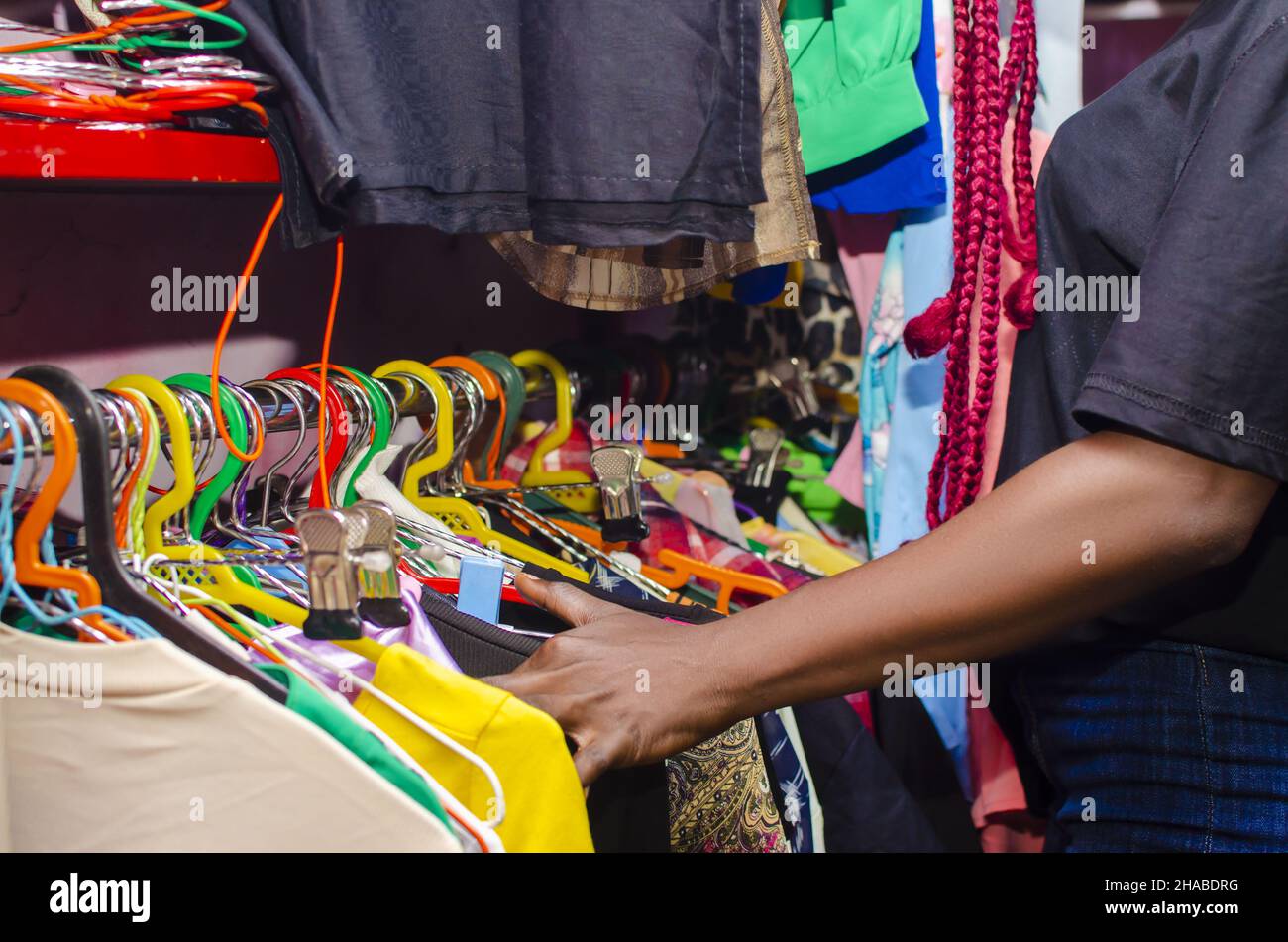 Una bella ragazza nigeriana nera con capelli rossi rasta che esplorano giacche alla BOUTIQUE Foto Stock