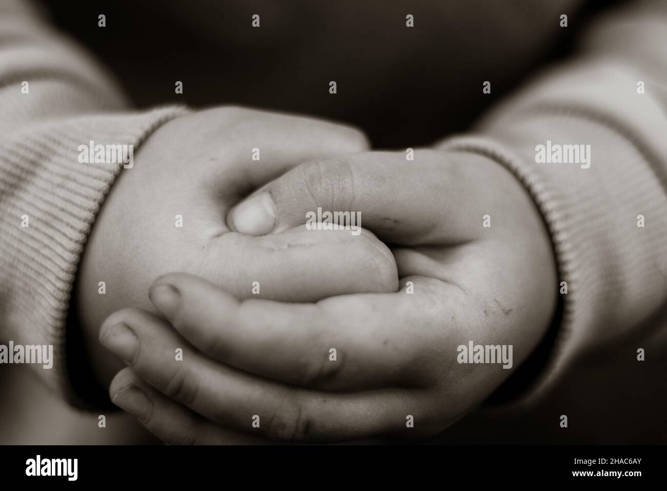 Il genitore tiene la mano di un bambino piccolo su sfondo sfocato astratto, fuoco morbido, tono bianco e nero Foto Stock