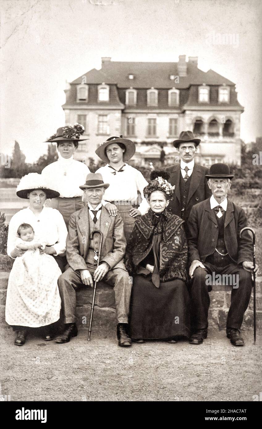Grande famiglia con casa sullo sfondo. Foto antica con grana originale Foto Stock