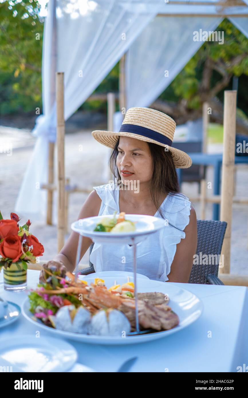 Cena romantica sulla spiaggia di Phuket Thailandia, donna asiatica di mezza età che ha cena sulla spiaggia in Thailandia durante il tramonto. Foto Stock