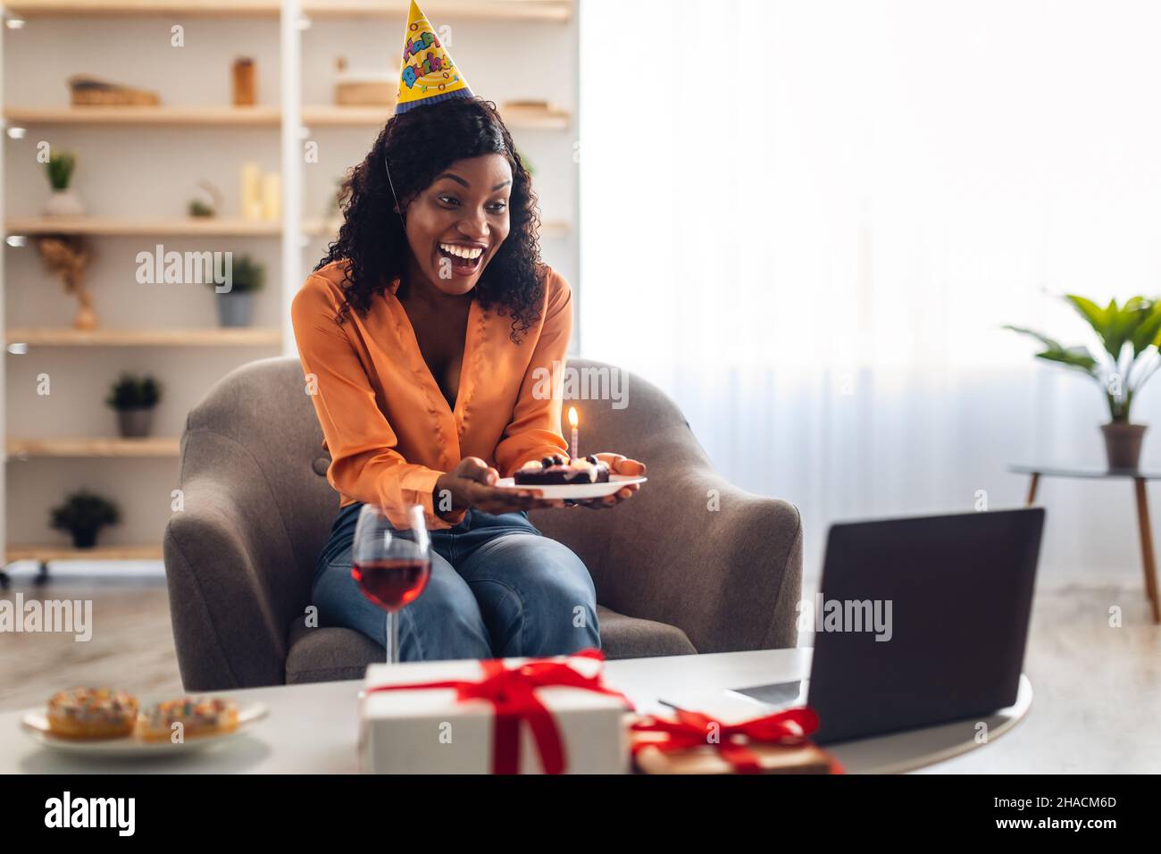 Donna africana che ha festa di B-Day che mostra torta al notebook indoor Foto Stock