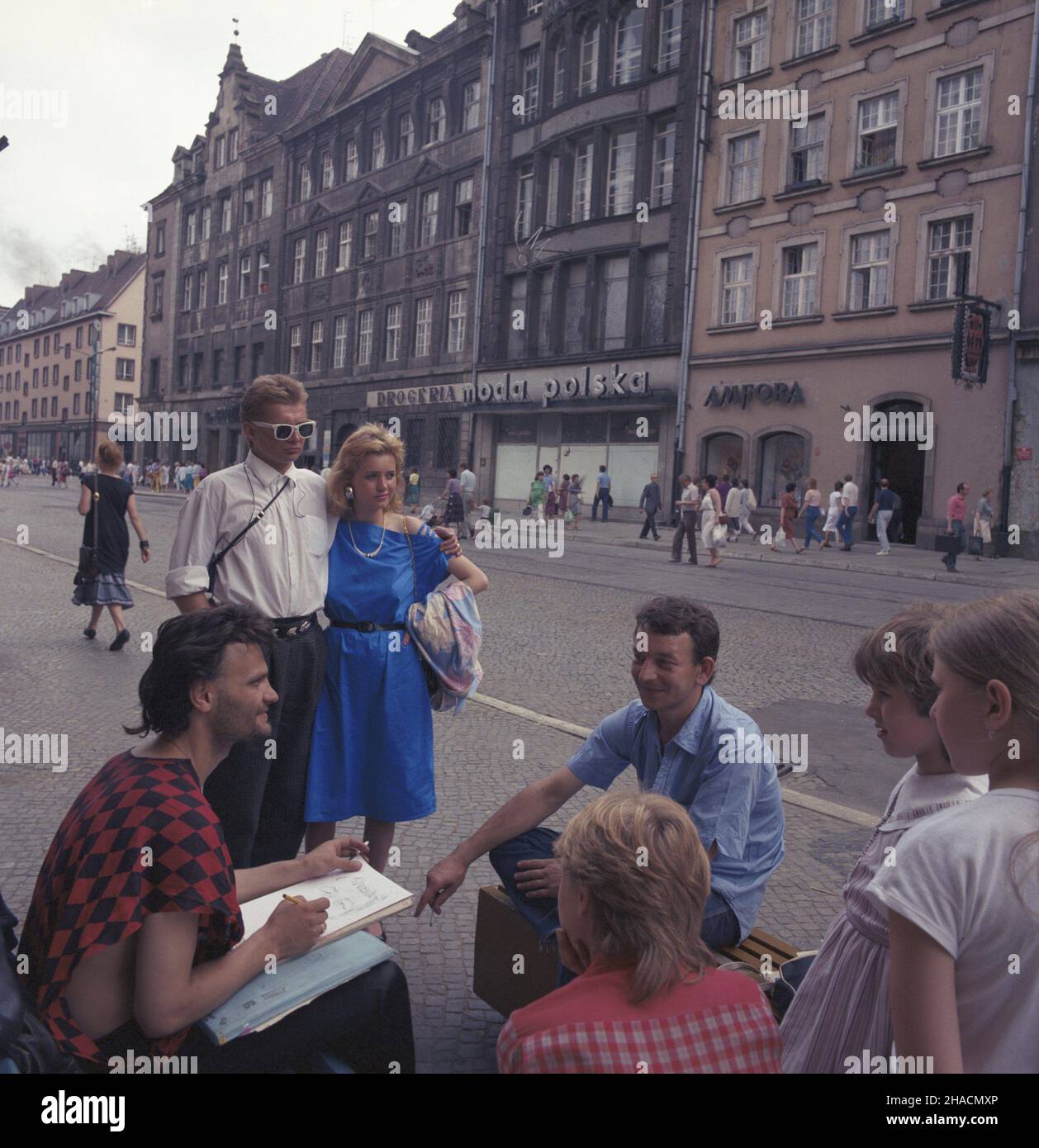 Wroc³aw 07.1987. Uliczny rysownik na Rynku, w g³êbi sklep Amfora z kryszta³ami i szk³em ozdobnym (Rynek 22/24), obok salon Mody Polskiej (Rynek 25). uu PAP/Jan Morek Dok³adny dzieñ wydarzenia nieustalony. Wroclaw, Polonia, luglio 1987. Un artista di strada attira i ritratti dei turisti alla Piazza del mercato nel centro storico di Breslavia. PAP/JAN MOREK Foto Stock