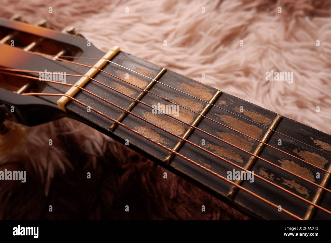 Chitarra usata con filo metallico rotto su un tappeto Foto Stock