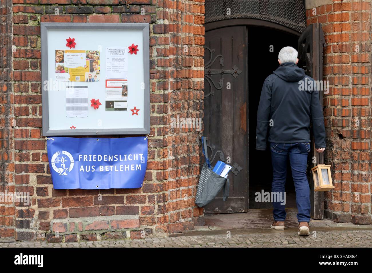 Stendal, Germania. 12th Dic 2021. Un uomo va al servizio della luce della Pace nella Cattedrale protestante di San Nicola. Più di 150 scout hanno dato l'esempio del dialogo interreligioso secondo il motto di quest'anno della luce della Pace "rete della Pace - una luce che collega tutti". Credit: Peter Gercke/dpa-Zentralbild/ZB/dpa/Alamy Live News Foto Stock