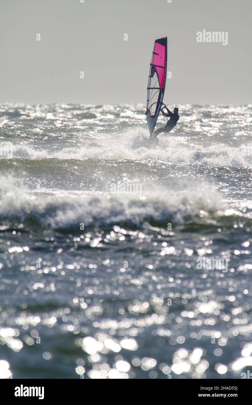Windsurf vela Equitazione onde su Un mare agitato in Christchurch Bay UK Foto Stock