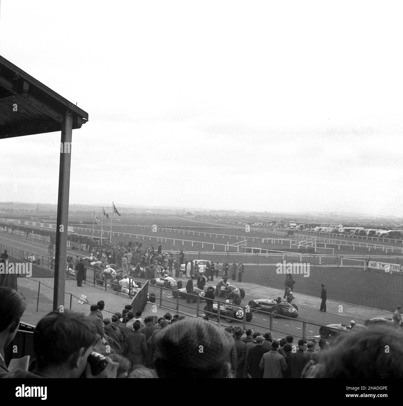 1950s, vista storica, lontana dalla tribuna di un evento motoristico, Inghilterra, Regno Unito, forse il Gran Premio di Gran Bretagna al famoso ippodromo di Aintree, Liverpool. Sperando di aumentare la vitalità dell'ippodromo, la nuova proprietaria di Aintree, la signora Topham, costruì un circuito automobilistico di tre miglia all'interno dell'ippodromo, utilizzando le strutture per spettatori già in atto. Foto Stock