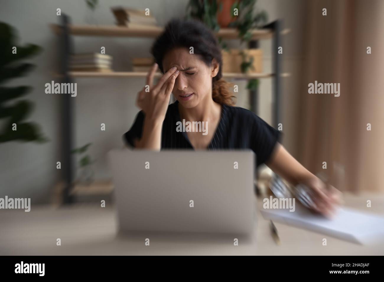 Donna malsana lotta con visione offuscata sul posto di lavoro Foto Stock