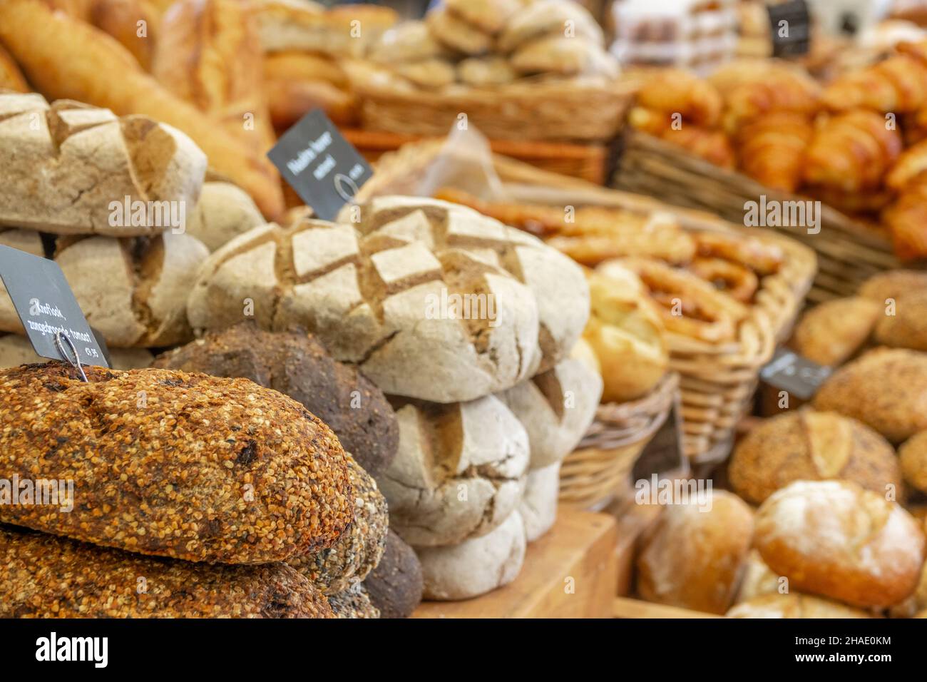 Paesi Bassi. Mercato agricolo ad Amsterdam. Molti tipi di pane e croissant. Il cartello in primo piano recita 'aglio, pomodoro essiccato al sole' in olandese Foto Stock