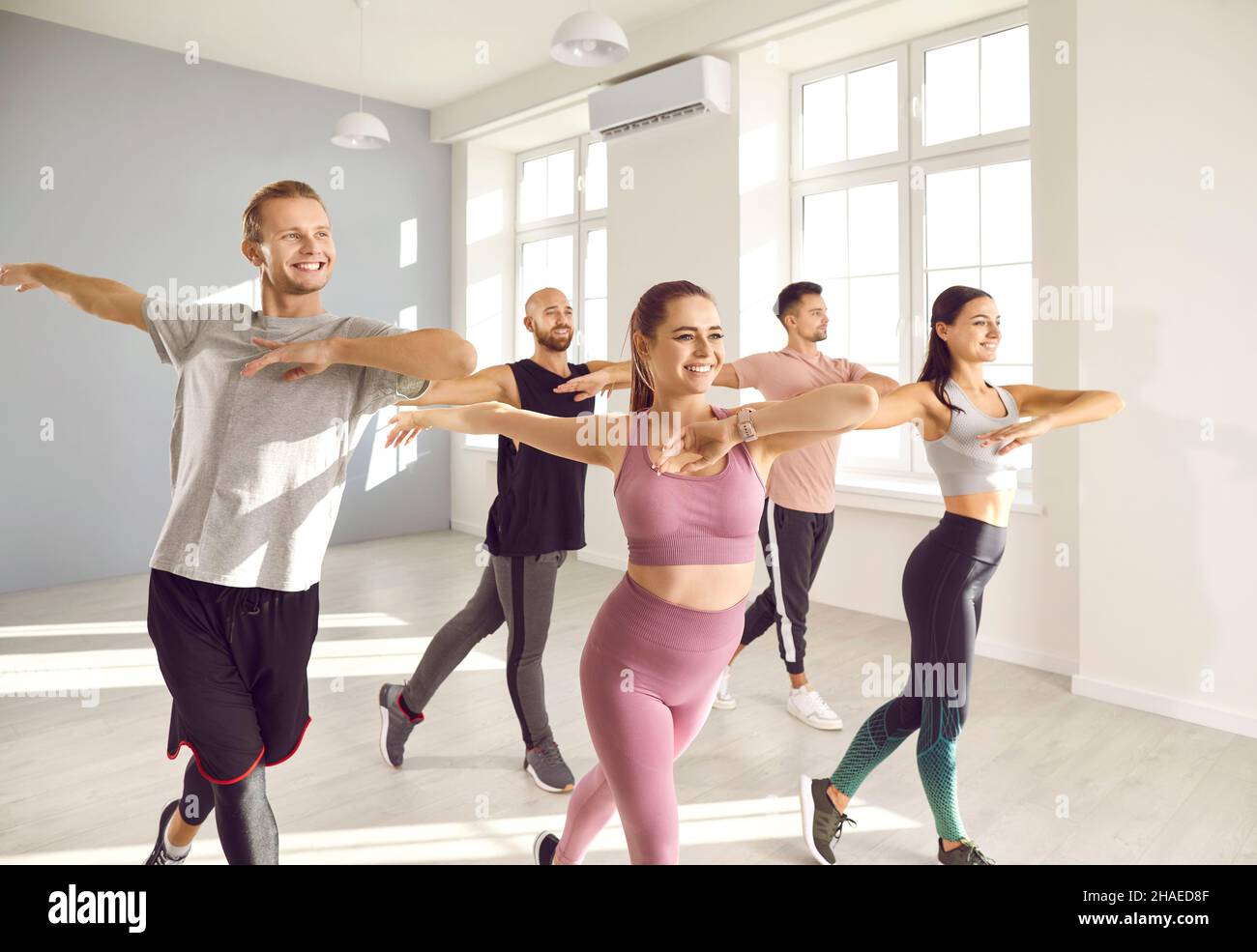 Gruppo di giovani felici e sorridenti che hanno allenamento fitness danza con istruttore Foto Stock