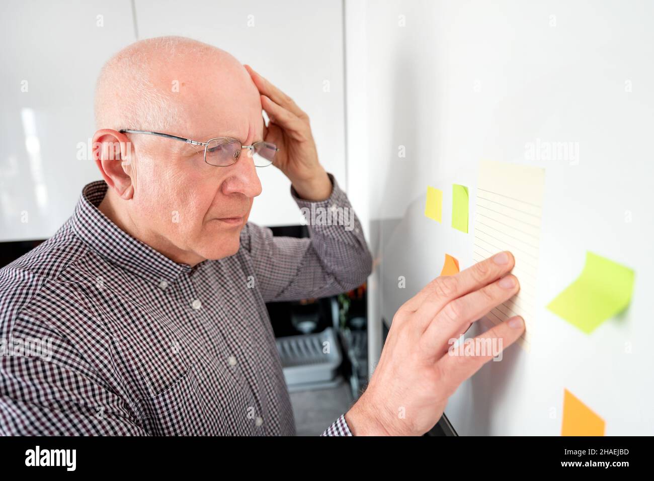 Uomo anziano guardando le note. Dimentico senior con demenza, il problema di memoria, il concetto di salute Foto Stock
