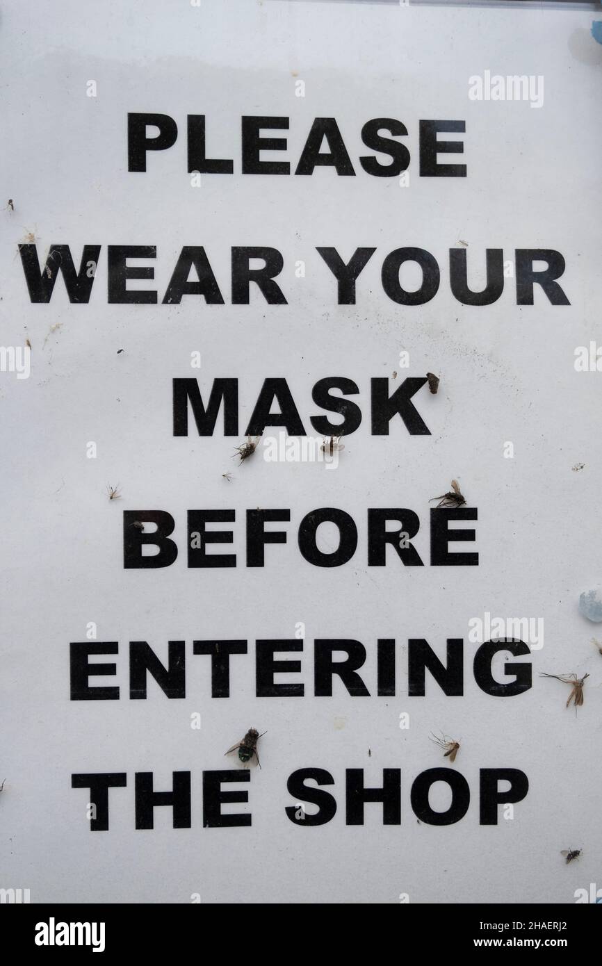 Il 11th novembre 2021 a Lynton, Regno Unito, la maschera di coronavirus cavalcata di volo in una vetrina. Si prega di indossare la maschera prima di entrare nel negozio. Foto Stock