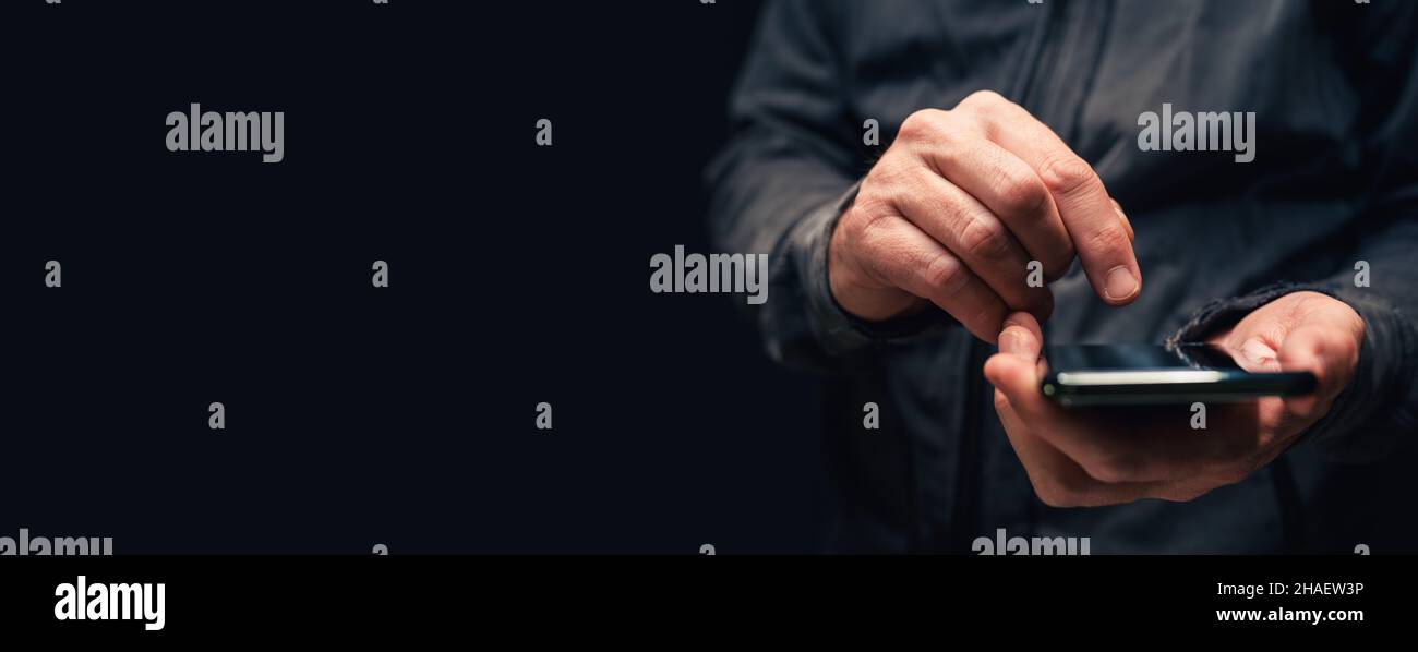 Primo piano panoramico delle mani maschili con smartphone per la comunicazione di messaggi di testo, spazio di copia incluso in questa immagine a basso tasto con messa a fuoco selettiva Foto Stock