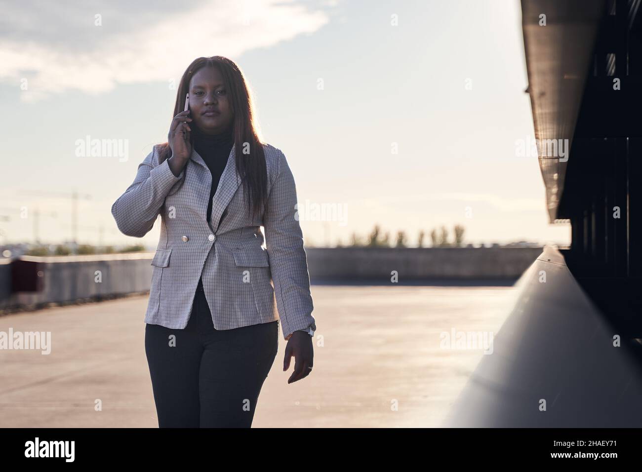 donna d'affari che parla su smartphone. Donna afroamericana in plaid bianco. Foto Stock
