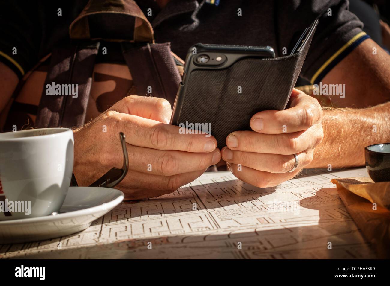 Mani di uomo usando il telefono cellulare all'esterno seduto ad un tavolo francese Street cafe Foto Stock
