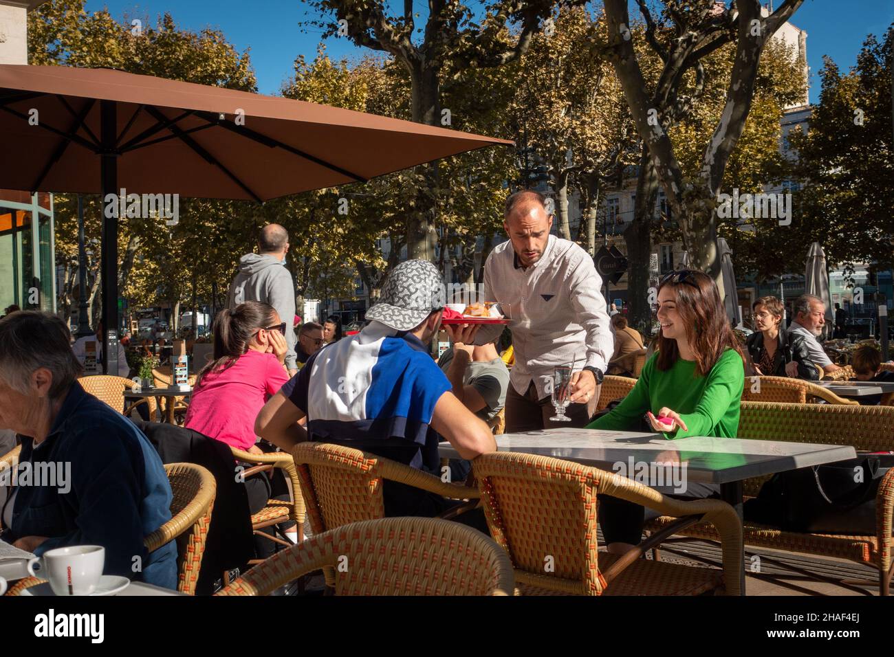 Un cameriere che serve i clienti in un caffè di strada francese Foto Stock