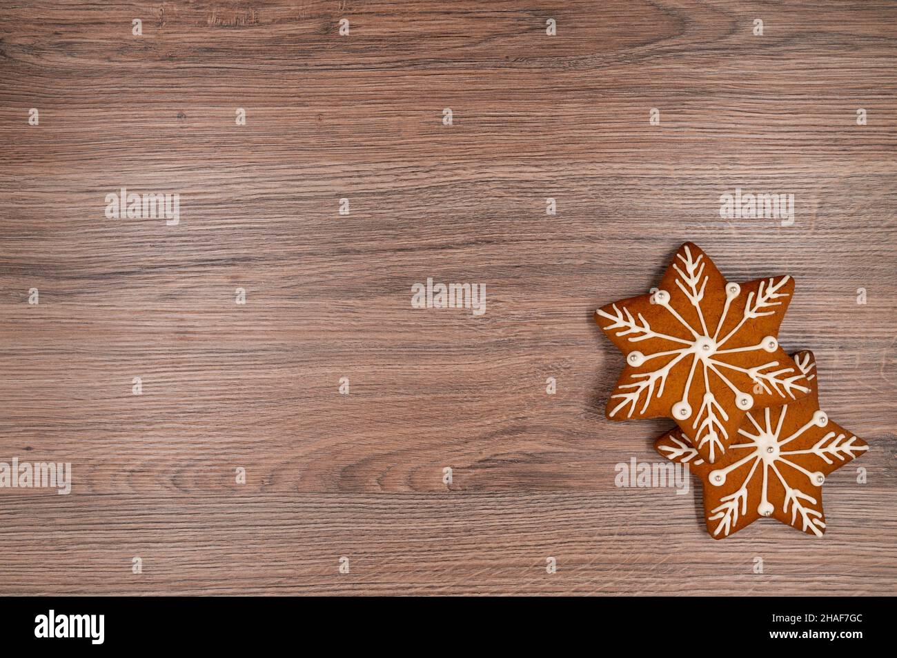 Due stelle di pan di zenzero con glassa bianca e perle d'argento su un tavolo di legno. Spazio di copia. Vista dall'alto. Foto Stock