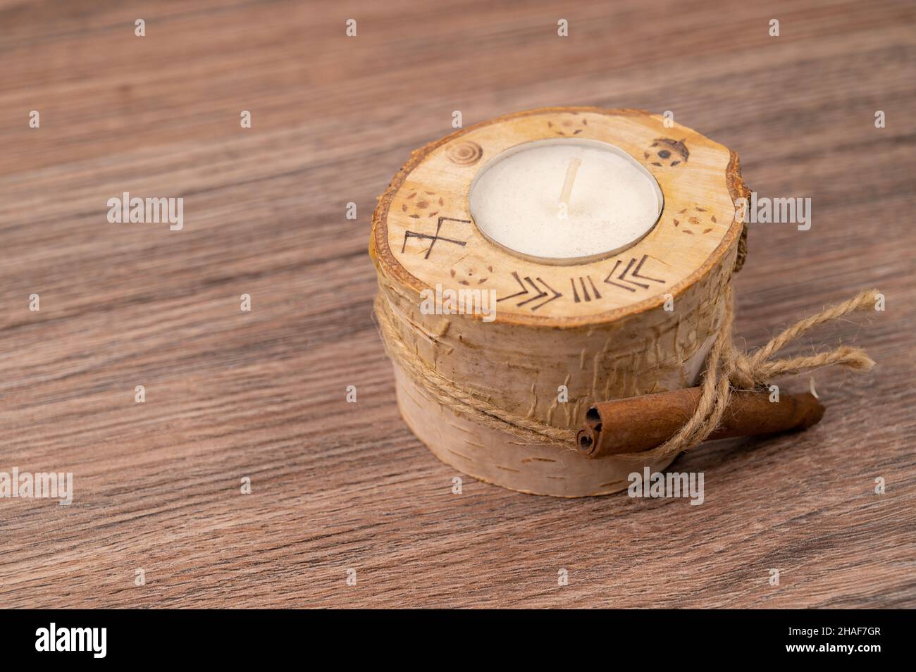 Primo piano di una candela di Natale posta in un ramoscello di betulla fatto a mano e bastone di cannella attaccato. Foto Stock