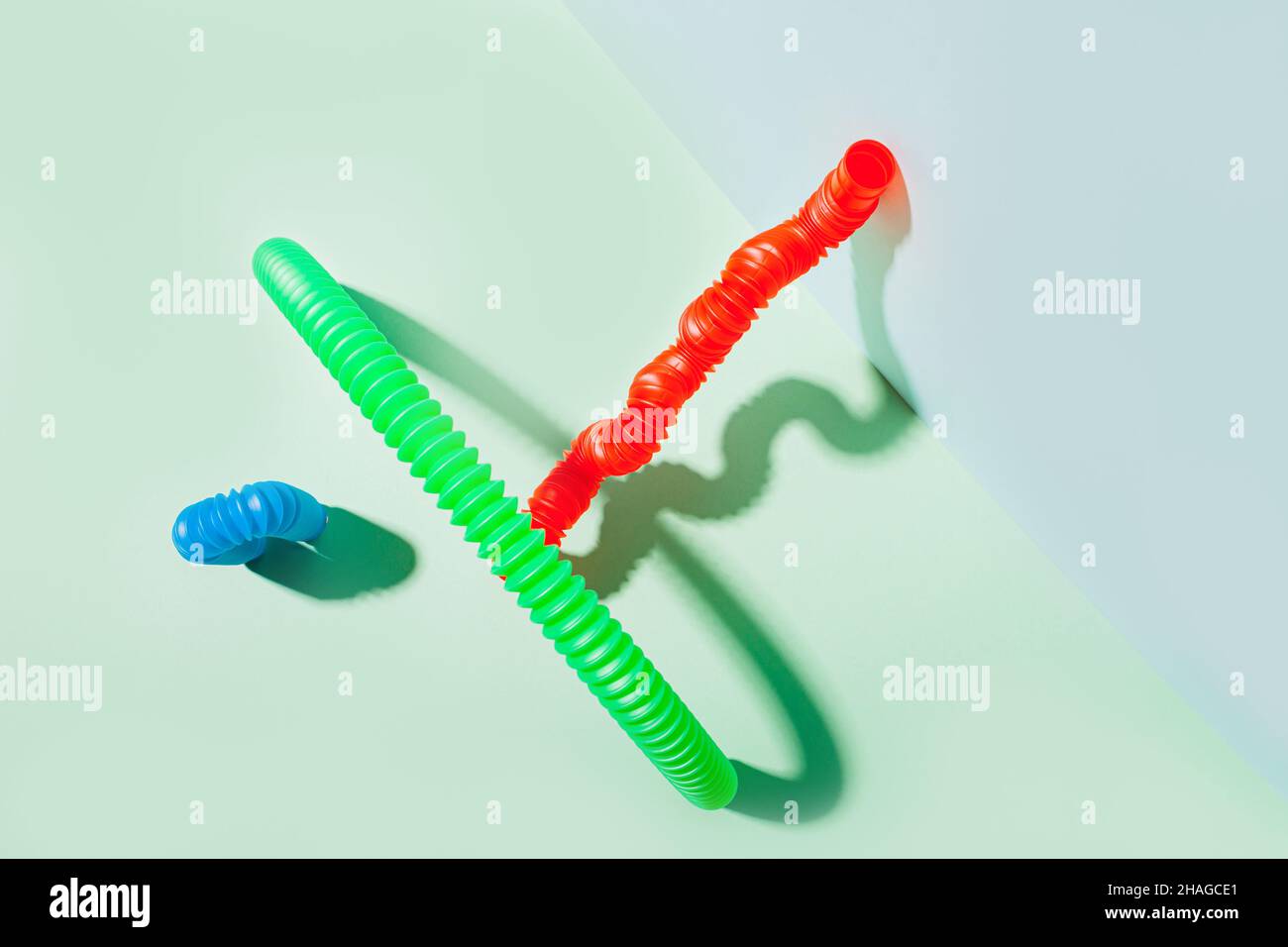 Il tubo pop curvo è appoggiato contro la parete. Vita morta moderna con giocattolo antistress. Foto Stock