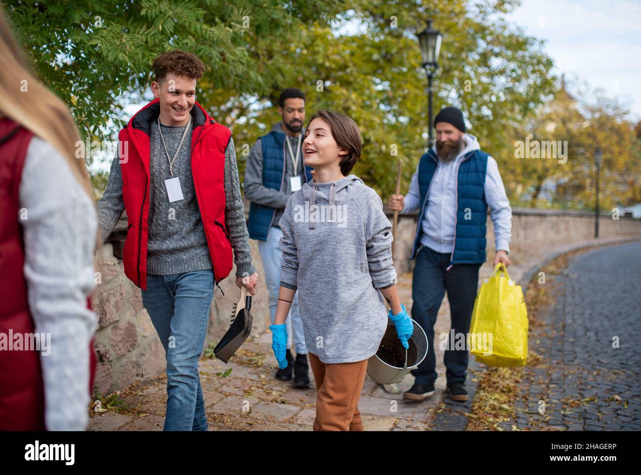 Un gruppo di volontari felici che camminano con gli strumenti per pulire la strada, concetto di servizio comunitario Foto Stock