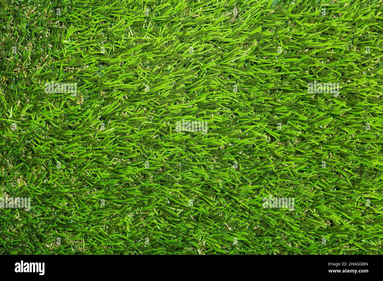 Fondo erboso artificiale. Erba di plastica artificiale verde per coprire il pavimento o il terreno. Foto di alta qualità Foto Stock