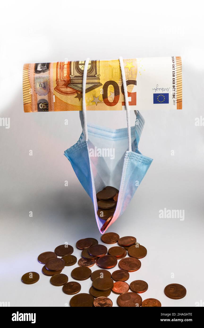 L'effetto economico della pandemia - Una banconota da 50 euro contiene una maschera protettiva riempita di centesimi di euro, concetto per dimostrare l'impoverimento Foto Stock