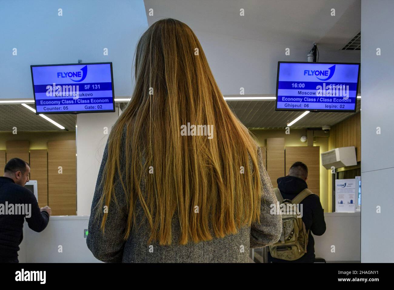 Moldavia, Chisinau - Dicembre 2019: Ragazza con capelli biondi lunghi in attesa della registrazione del volo per Mosca all'aeroporto di Chisinau. Vista posteriore. Foto Stock