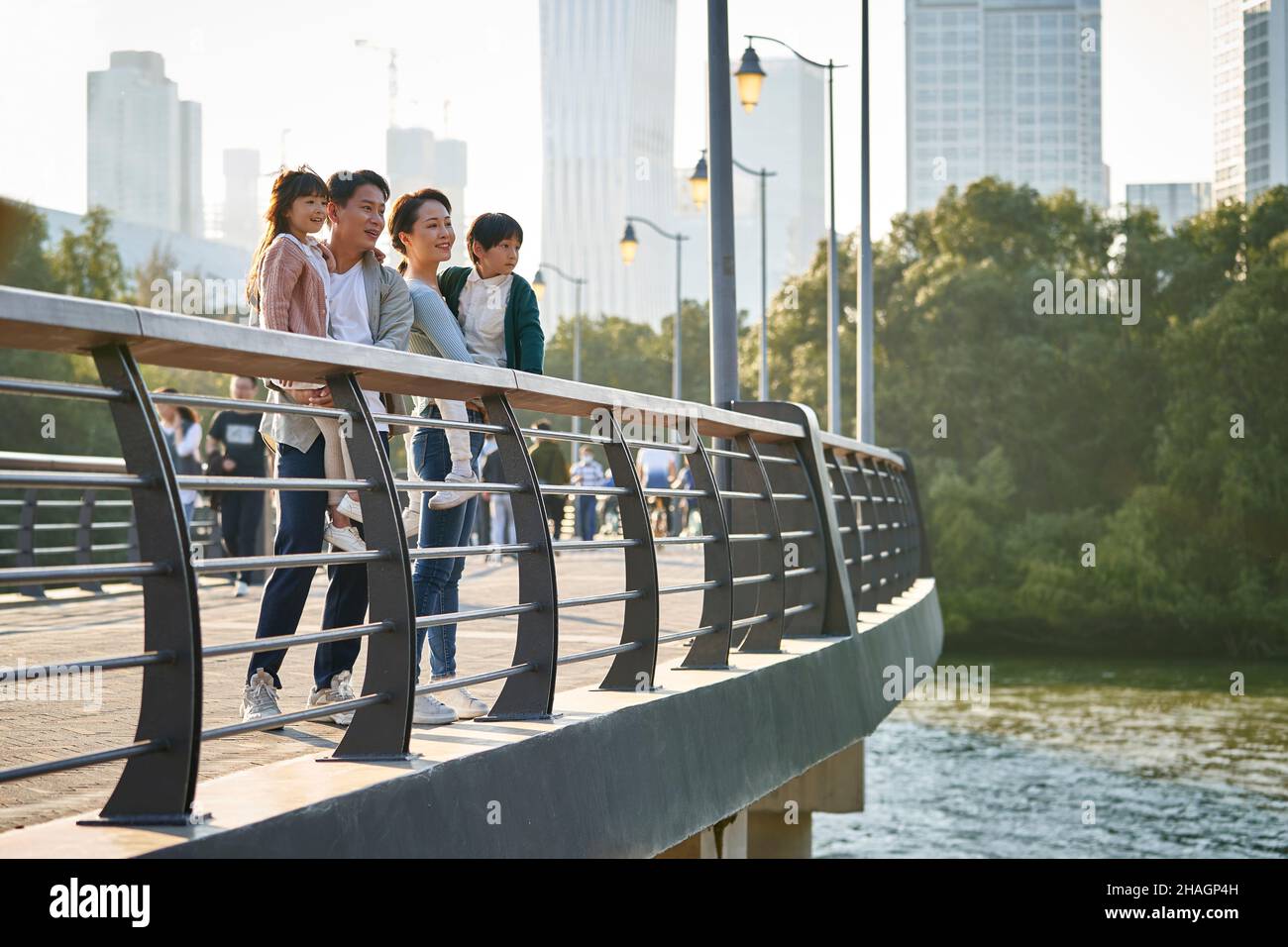 famiglia asiatica con due bambini in piedi su un ponte pedonale che guarda la vista del parco cittadino Foto Stock