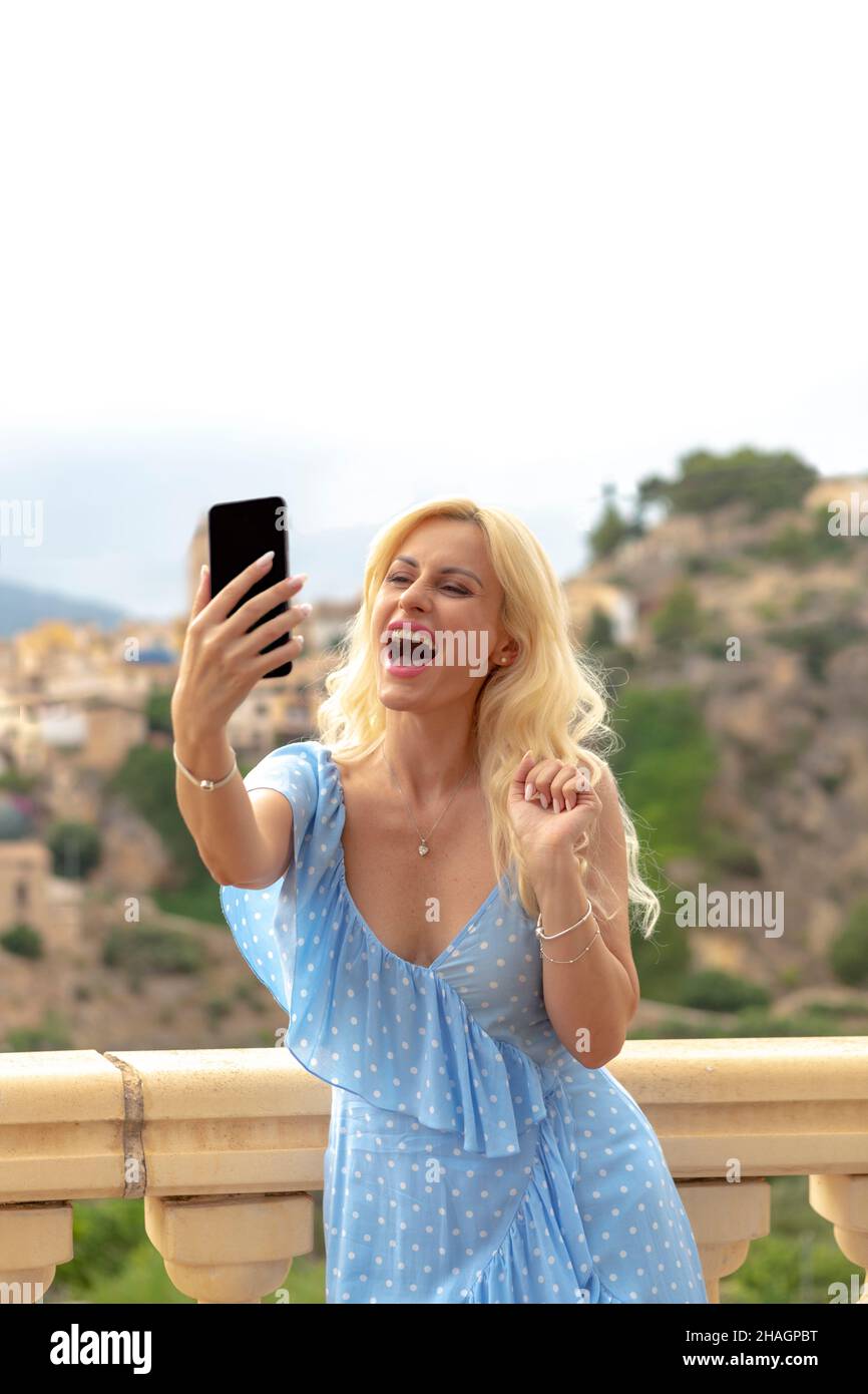 bella donna bionda nel suo 40s prendendo selfie Foto Stock
