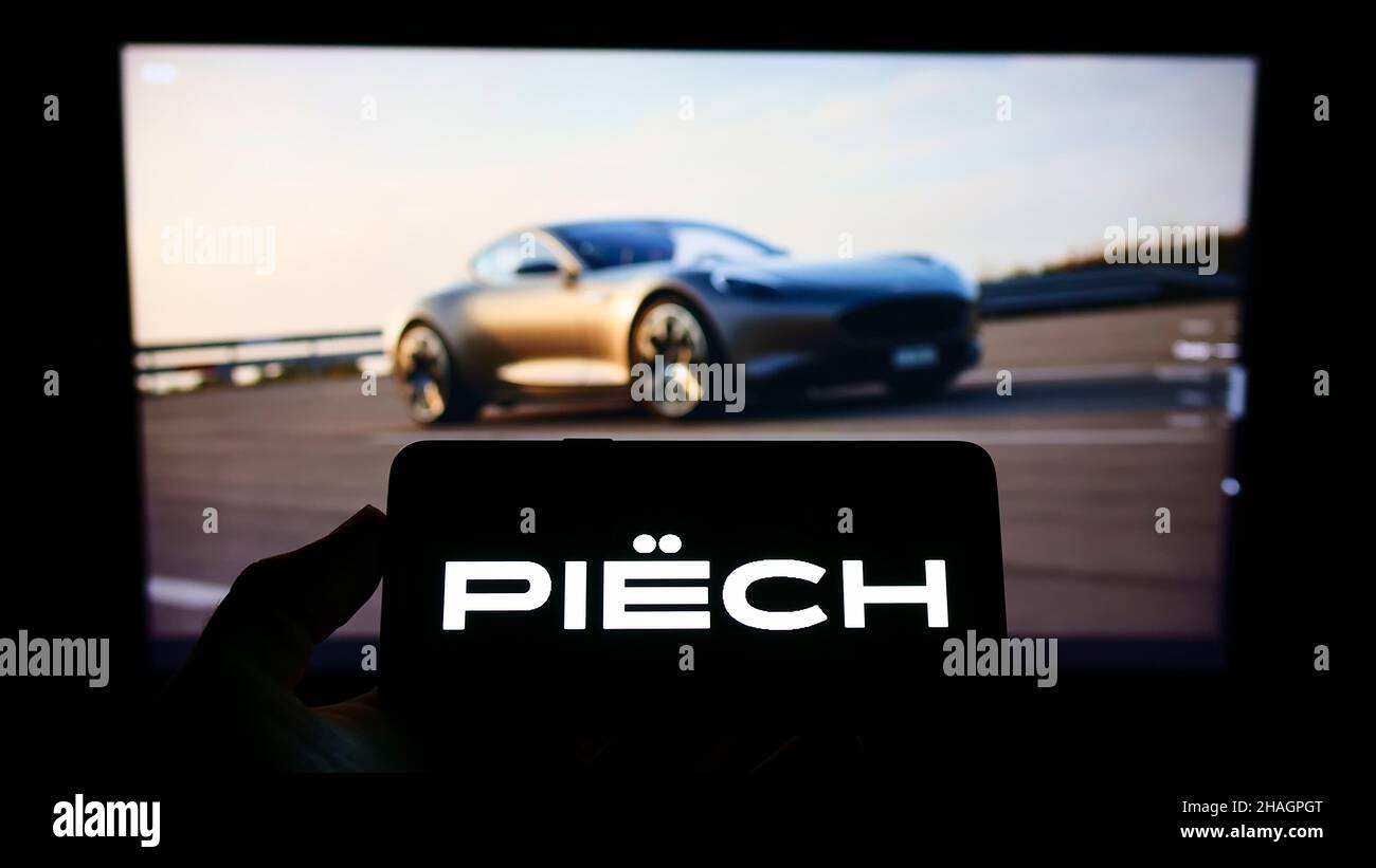 Persona che tiene il cellulare con il logo della società di auto elettrica Piech Automotive AG sullo schermo di fronte al sito web aziendale. Mettere a fuoco sul display del telefono. Foto Stock